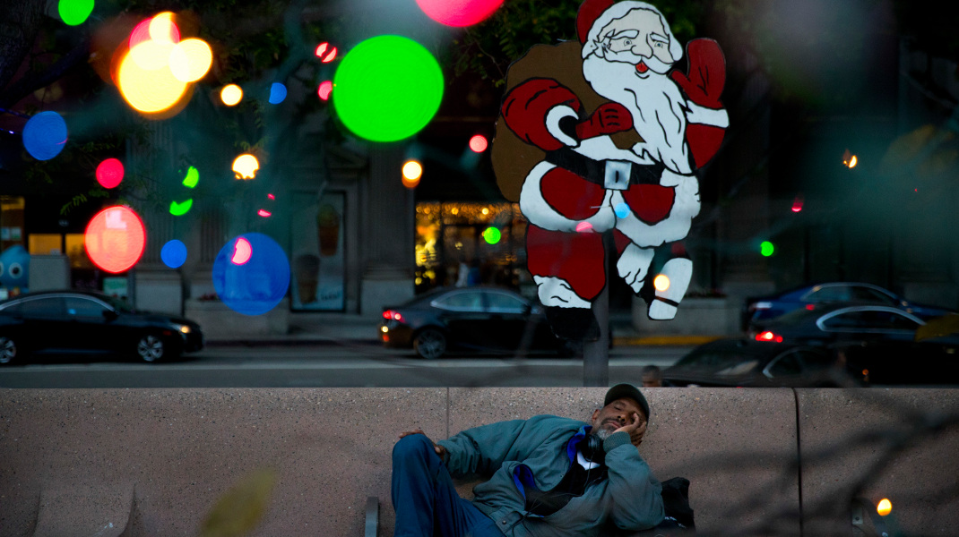 Το θλιβερό κοντράστ: Αστεγος με φόντο χριστουγεννιάτικο στολισμό -Φωτογραφία: AP Photo/Jae C. Hong
