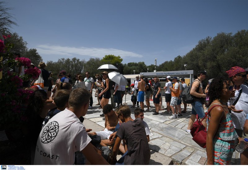 Τουρίστες περιμένουν υπομονετικά κάτω από τον ήλιο