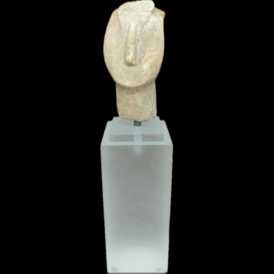 Μαρμάρινη κεφαλή Κυκλαδικού ειδωλίου. Ανήκει στον σπανιότερο τύπο του συμπλέγματος κατακόρυφης διάταξης. Στο μέσον του μετώπου διατηρούνται τα ίχνη των άκρων των ποδιών της μικρότερης μορφής η οποία πατούσε στην κεφαλή της μεγαλύτερης. Ύψος 5,14 εκ. Πρωτοκυκλαδική ΙΙ περίοδος (2500-2400 π.Χ.).