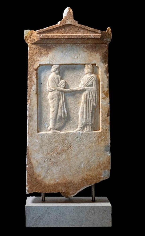 Αττική μελανόμορφη κύλικα της «Κατηγορίας του αποτμήματος». Στο εσωτερικό του αγγείου απεικονίζεται Διονυσιακή σκηνή: τρεις Μαινάδες που χορεύουν. Στο απότμημα κρατήρας εκατέρωθεν ψαριών. Διάμετρος 17,65 εκ. Ύστερος 6ος αι. π.Χ.