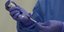 εμβόλιο σε νοσηλεύτρια με μωβ γάντια και μπλε ιατρική στολή
