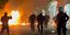 Αζτυνομικοί τρέχουν μπροστά από φωτιές που προκλήθηκαν από βόμβες μολότοφ σε πορεία για το Πολυτεχνείο στην Πάτρα