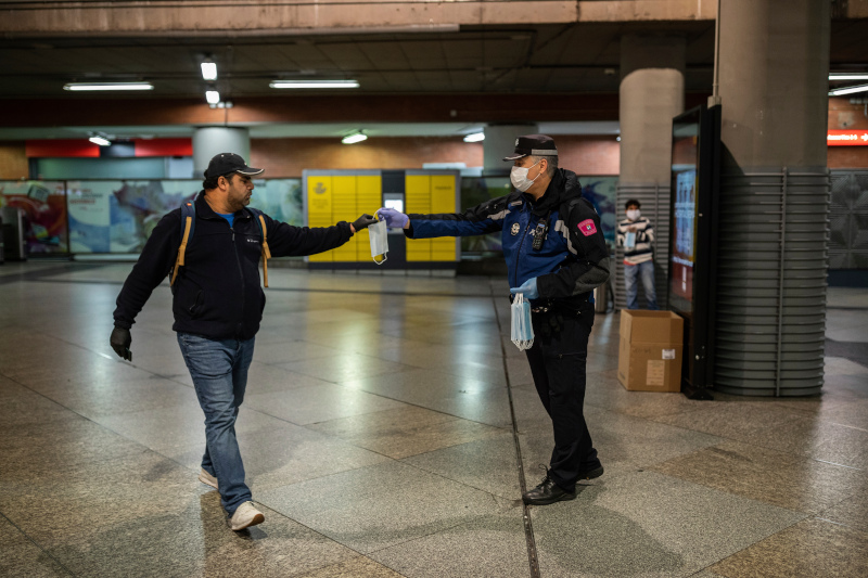 Αστυνομικός μοιράζει μάσκες προσώπου στο σιδηροδρομικό σταθμό Atocha της Μαδρίτης