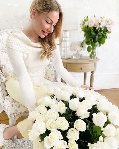 Γυναίκα μπροστά σε ανθοδέσμη με λευκά τριαντάφυλλα 