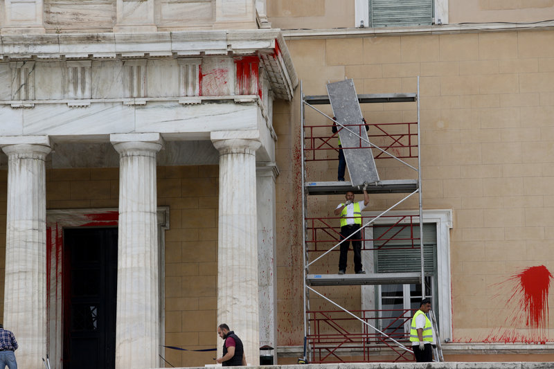 Υπάλληλοι συνεργείων καθαρισμού τοποθετούν σκαλωσιές για να καθαρίσουν τις μπογιές που πέταξαν τα μέλη του Ρουβίκωνα