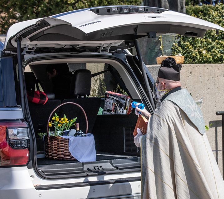 Ο ιερέας Τίμοθι Πελκ ψεκάζει αγιασμό σε ένα καλάθι με λουλούδια
