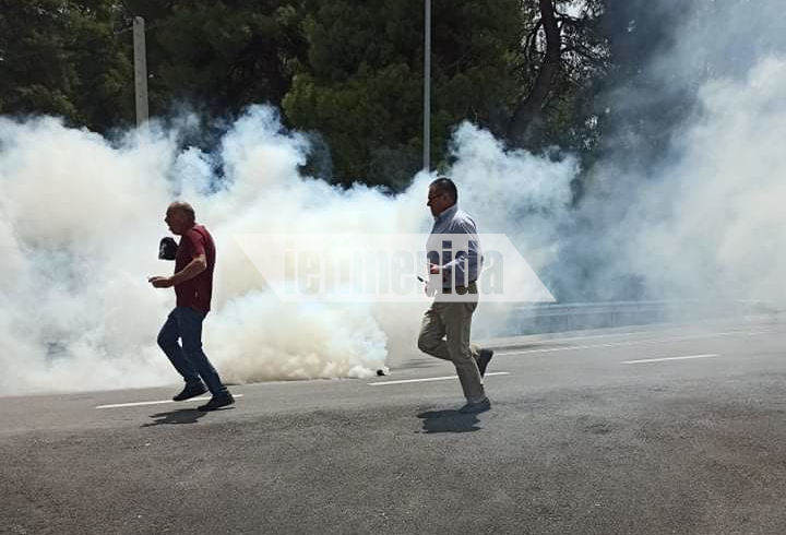 Δυο άνδρες τρέχουν στο οδόστρωμα μέσα σε καπνό χημικών