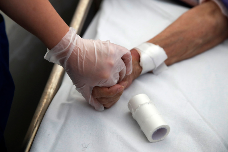 Η φοιτήτρια ιατρικής Μιχαέλα Αλεξάνδρου κρατά το χέρι ασθενούς όσο η συνάδερφός της παίρνει αίμα από ασθενή στο νοσοκομείο «Σωτηρία» 