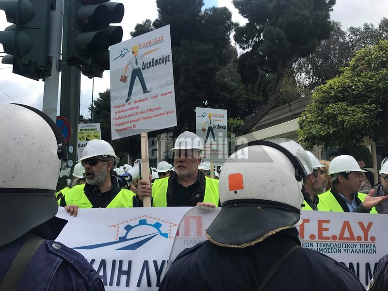 Μηχανικοί κρατούν πλακάτ μπροστά από αστυνομικούς