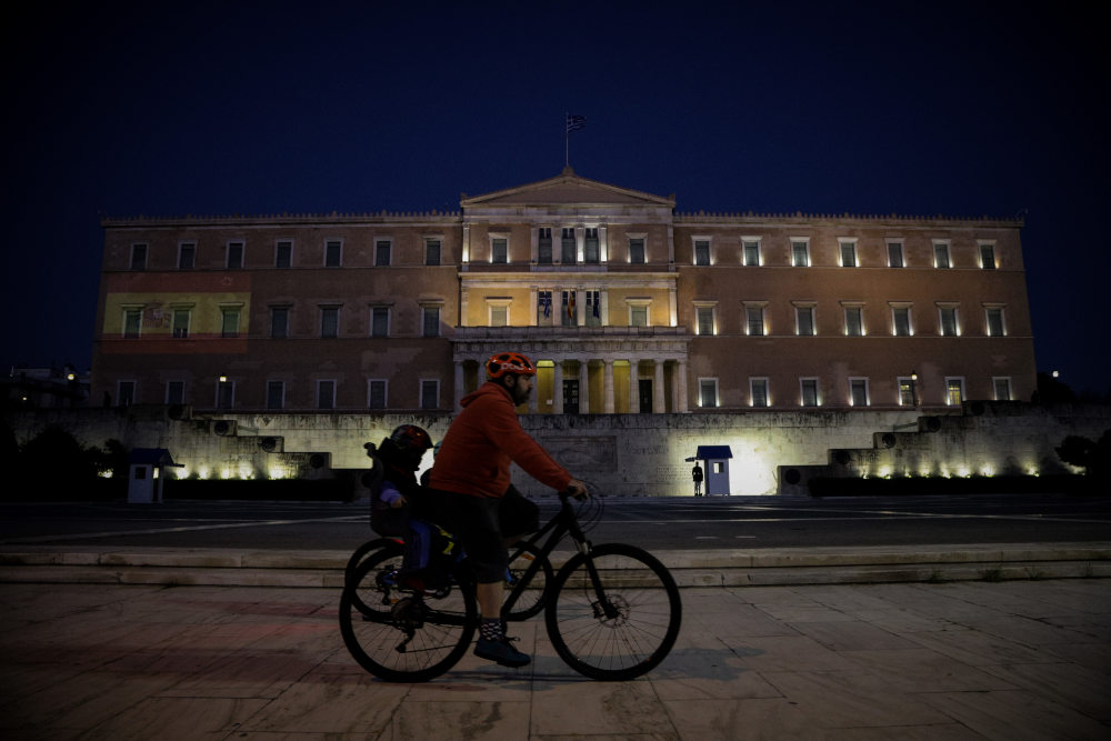 Ποδηλάτης στο κέντρο της Αθήνας, μπροστά από την Βουλή των Ελλήνων, όπου φέγγει η σημαία της Ισπανίας