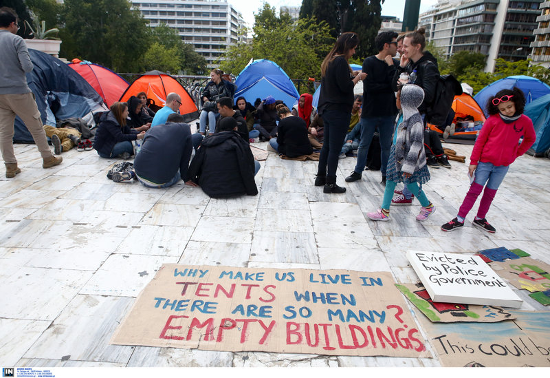 «Γιατί μας έχουν να μένουμε σε σκηνές όταν υπάρχουν τόσα άδεια κτίρια;» λέει το πρόχειρο πλακάτ -Φωτογραφία: Intimenews/ΣΤΕΦΑΝΟΥ ΣΤΕΛΙΟΣ
