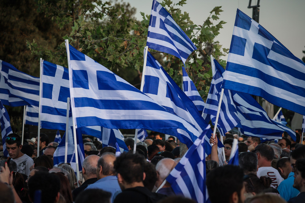 Οι οπαδοί της Νέας Δημοκρατίας κρατούν ελληνικές σημαίες αναμένοντας τον Κυριάκο Μητσοτάκη