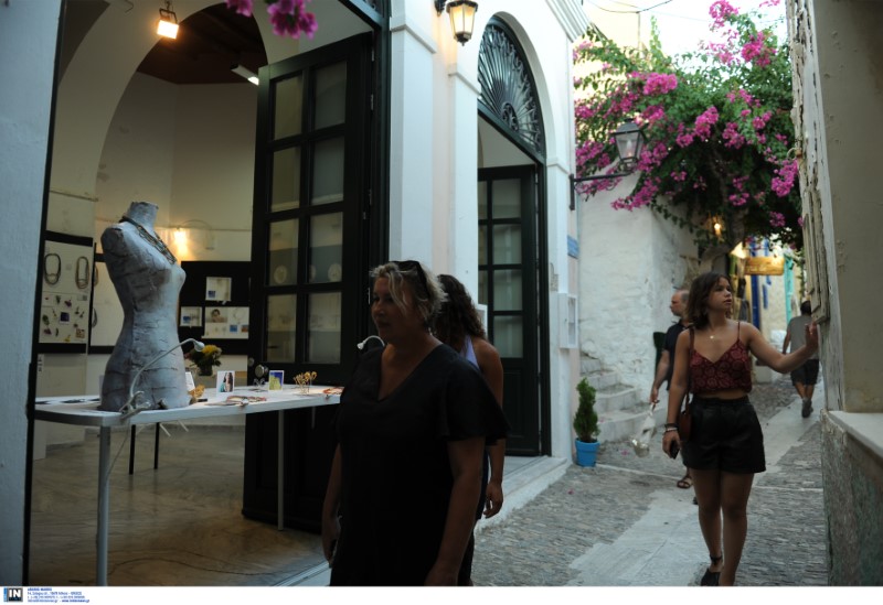 Τουρίστες σε σοκάκια νησιού με μαγαζιά τουριστικών ειδών