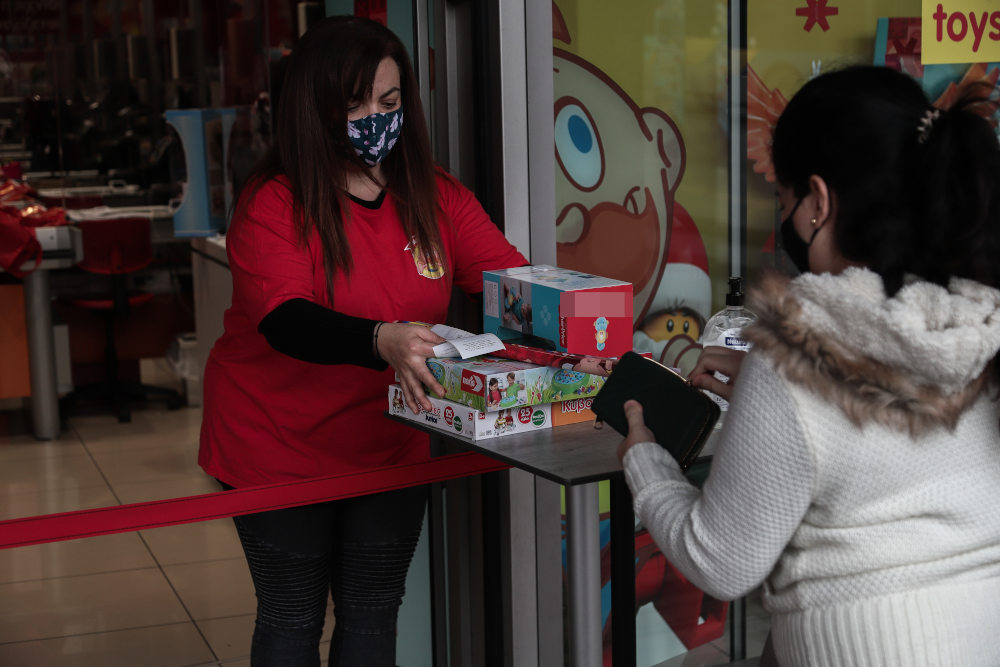 Εργαζόμενη σε κατάστημα παιχνιδιών παραδίδει την παραγγελία πελάτισσας στο κέντρο της Αθήνας