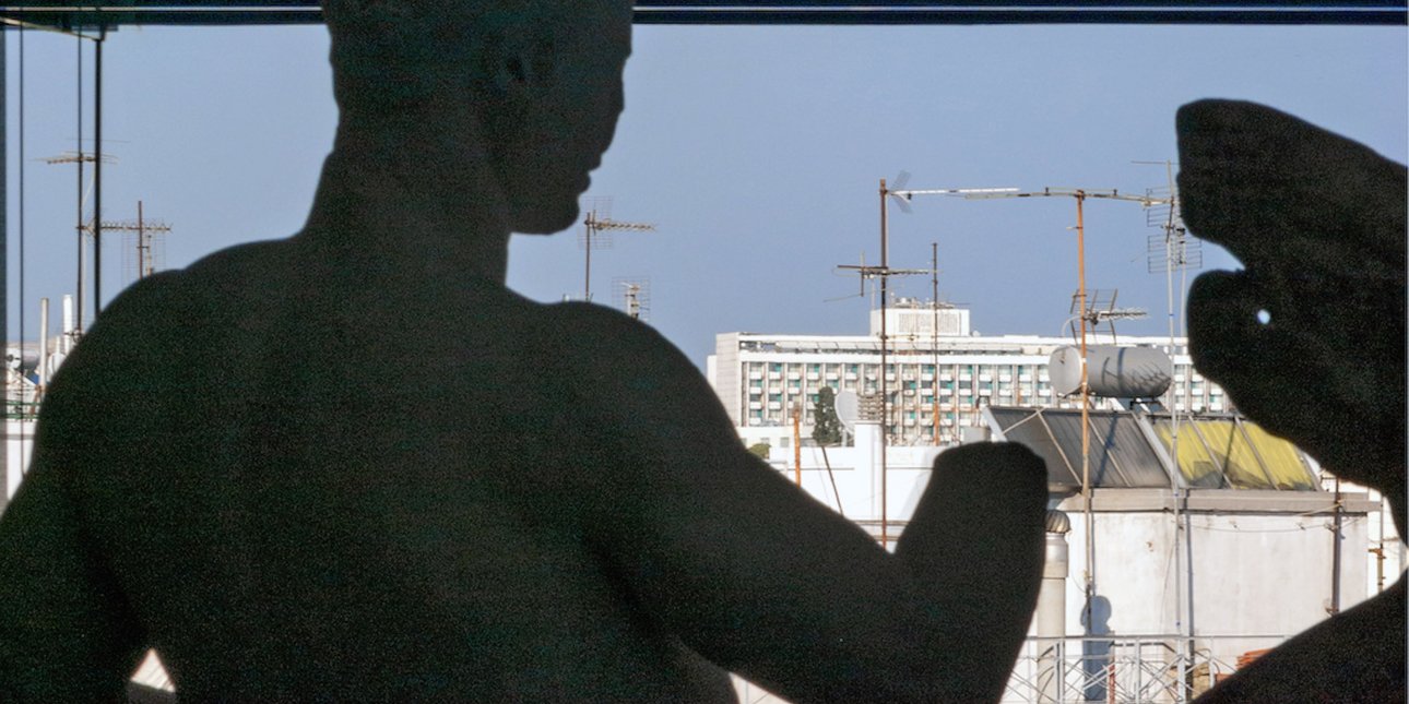 Αγαλμα από την αίθουσα Παρθενώνα κοιτά τις ταράτσες στην Πλάκα