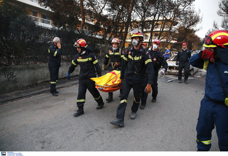 Διασώστες μεταφέρουν τη σορό ενός νεκρού στην περιοχή στο Μάτι