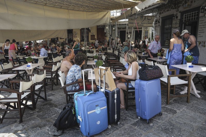 Τουρίστες στο λιμάνι, με τα μπαγκάζια τους παραμάσχαλα περιμένοντας το καταμαράν
