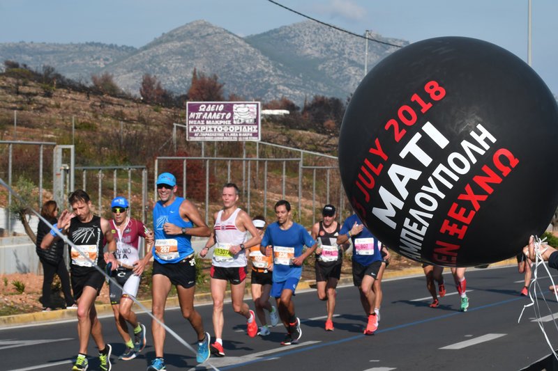 Η στιγμή που οι δρομείς περνούν μπροστά από τους πυρόπληκτους