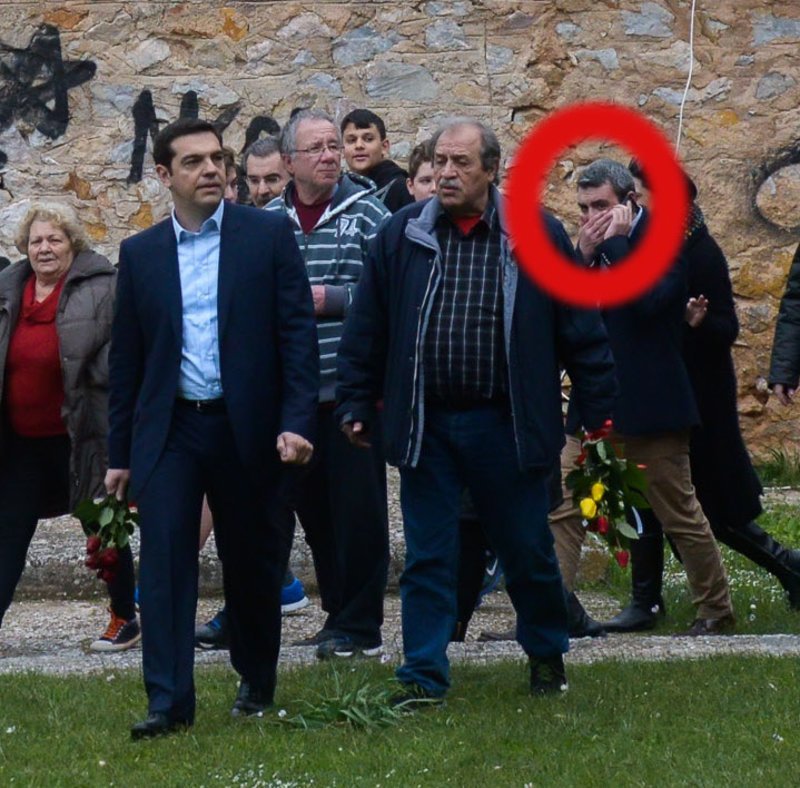 Ο Μανώλης Πετσίτης μιλά στο κινητό, δύο βήματα πίσω από τον πρωθυπουργό