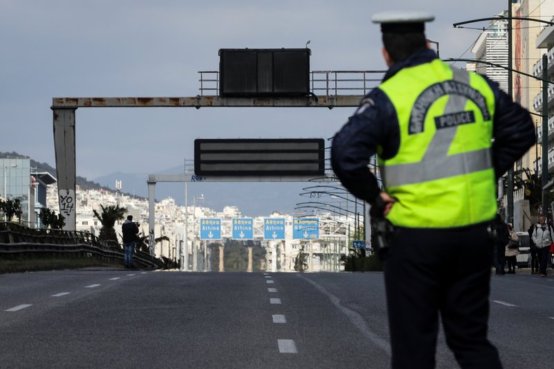Αστυνομικός κοιτάζει τον άδειο δρόμο και την ετοιμόρροπη πινακίδα / Φωτογραφία: EUROKINISSI/ ΓΙΑΝΝΗΣ ΠΑΝΑΓΟΠΟΥΛΟΣ