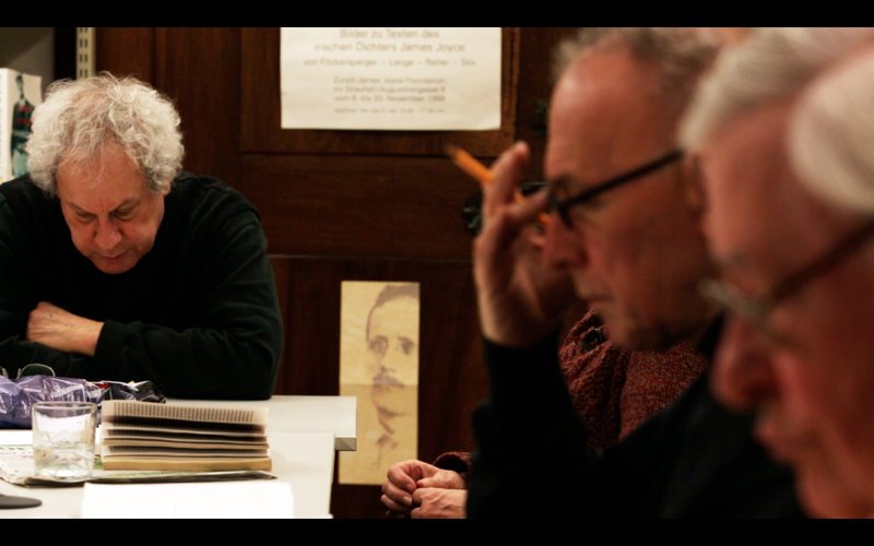 Ντόρα Γκαρθία Γεννήθηκε στο Βαγιαντολίντ, Ισπανία, 1965. Ζει και εργάζεται στη  Βαρκελώνη. «The Joycean Society» [Σύλλογος Φίλων του Τζόυς], 2013  Βιντεοεγκατάσταση, έγχρωμο, ήχος, 53, Ευγενική παραχώρηση: Auguste Orts, Bρυξέλλες  ©The Joycean Society by Dora Garcia Μια ομάδα αναγνωστών, Φίλοι του Ιδρύματος Τζέιμς Τζόυς  στη Ζυρίχη συναντώνται κάθε βδομάδα επί 30 χρόνια για να  διαβάσουν μαζί το πιο κρυπτικό μυθιστόρημα του Ιρλανδού  συγγραφέα, το Finnegans Wake [Η αγρύπνια των Φίννεγκανς],  δημοσιευμένο το 1939. 