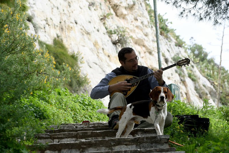 Ενας άνδρας παίζει μπουζούκι παρέα με τον σκύλο του στα δρομάκια του Λυκαβηττού
