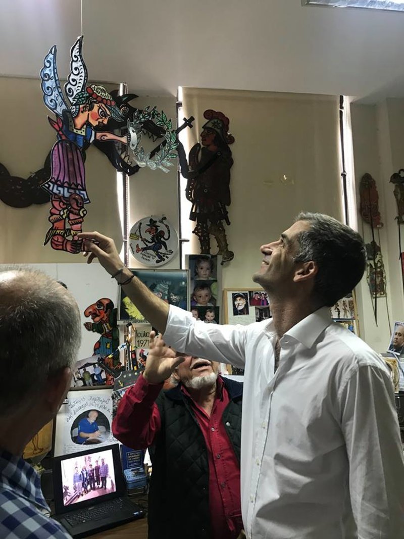 Ο υποψήφιος δήμαρχος Αθηναίων ευδιάθετος περιεργάζεται φιγούρα καραγκιόζη