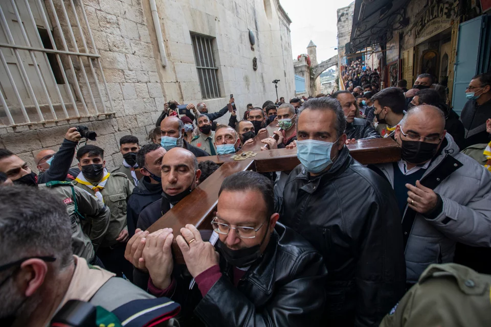 Πιστοί με μάσκες μεταφέρουν ξύλινο σταυρό στην Οδό του Μαρτυρίου στην παλιά πόλη της Ιερουσαλήμ