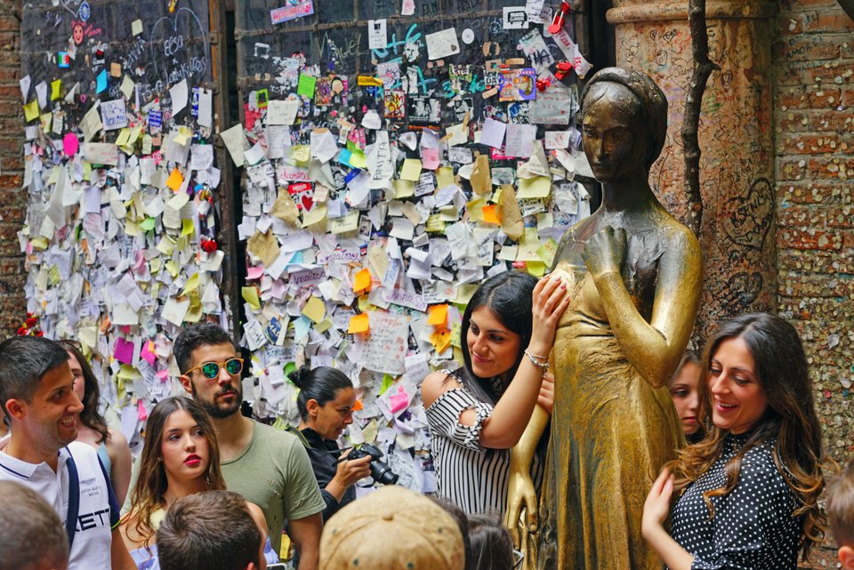 Κοπέλα ακουμπά το δεξί στήθος του αγάλματος της Ιουλιέτας και κόσμος γύρω της