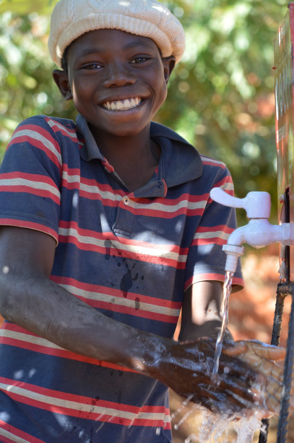 αγοράκι πλένει χαρούμενο τα χέρια του σε βρύση