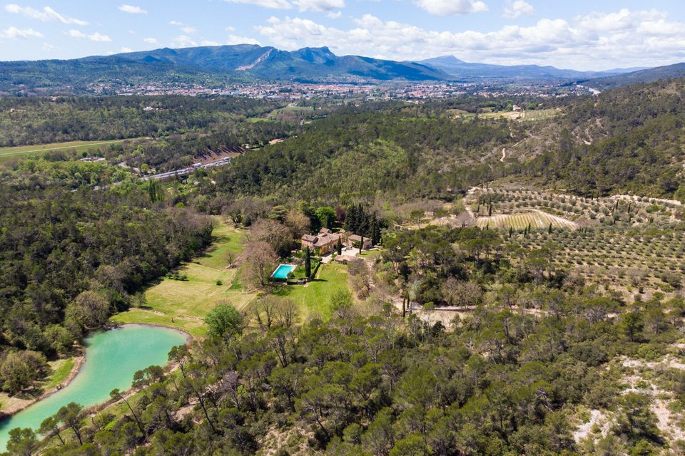 Πανοραμική άποψη του chateau, όπου διακρίνονται η πισίνα, οι αμπελώνες αλλά και η λίμνη