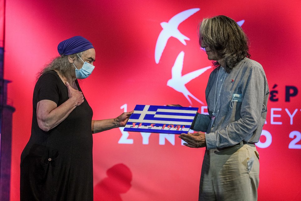 Η Τζώρτζια Γλέζου με τον συντονιστή της Κεντρικής Επιτροπής, Κώστα Μπιτσάνη παραλαμβάνει το δώρο που έφτιαξαν τα μέλη του ΜέΡΑ25 προς τιμήν του Μανώλη Γλέζου