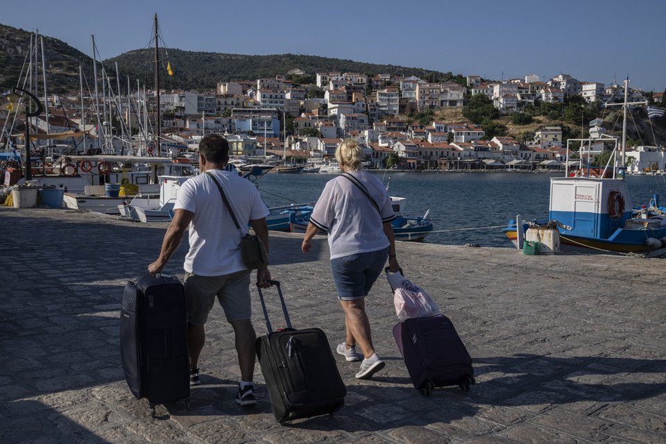 τουρίστες με αποσκευές σε ελληνικό νησί