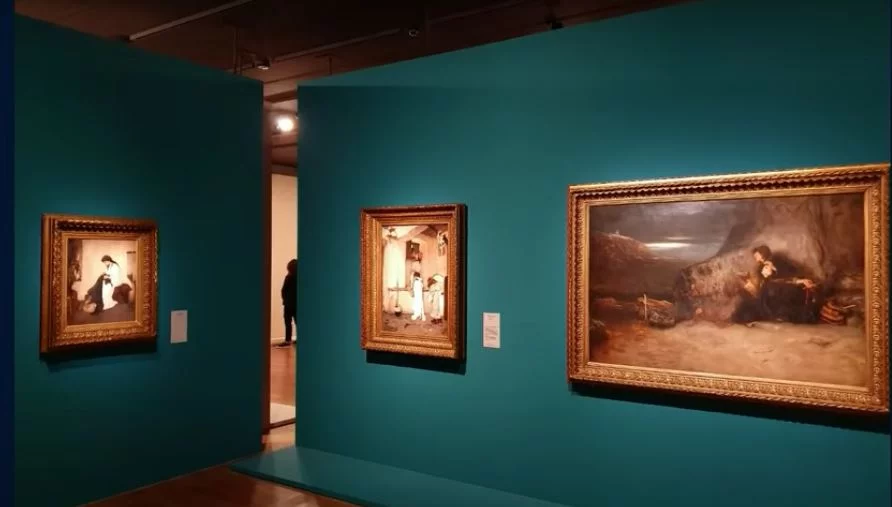 Στον τοίχο δεξιά βλέπουμε το «Τάμα» του Γύζη που εκτίθεται στο Μουσείο του Λούβρου, πλάι στην «Αναμονή» του Λύτρα