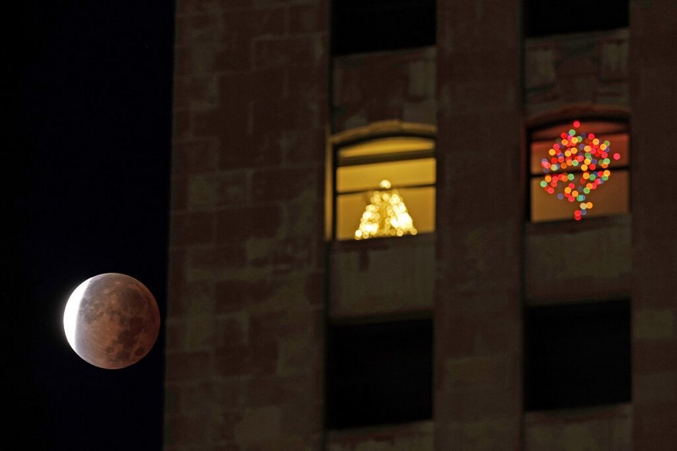 Η έκλειψη Σελήνης πλάι σε στολισμένο για τα Χριστούγεννα παράθυρα στο Μιζούρι των ΗΠΑ / Φωτογραφία: AP Photos