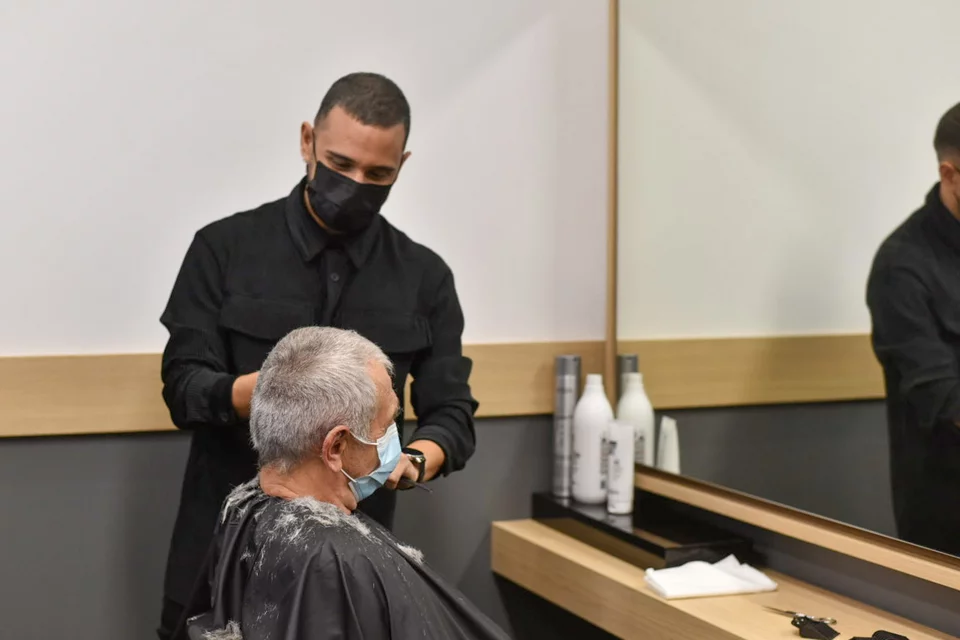 ο κομμωτής Αναστάσιος Σταυρόπουλος κουρεύει έναν άνδρα