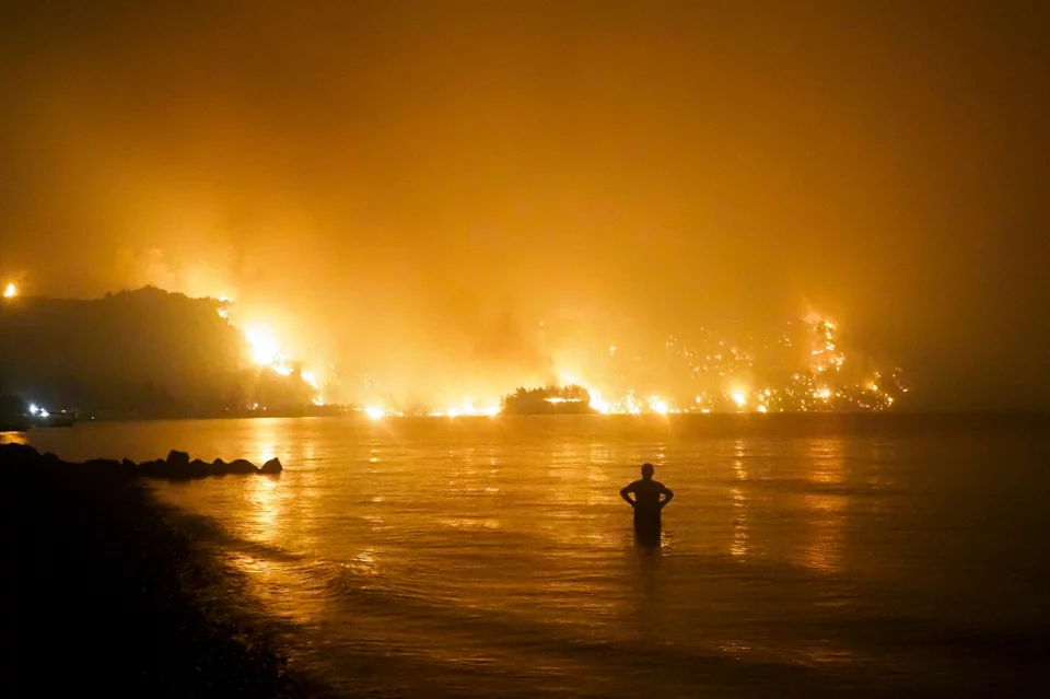 Ένας άνδρας παρακολουθεί μια πυρκαγιά να πλησιάζει την παραλία Κοχύλι κοντά στο χωριό Λίμνη στην Ελλάδα, περίπου 160 χιλιόμετρα βόρεια της Αθήνας, στις 6 Αυγούστου 2021. Φωτογραφία: AP Photo/Thodoris Nikolaou