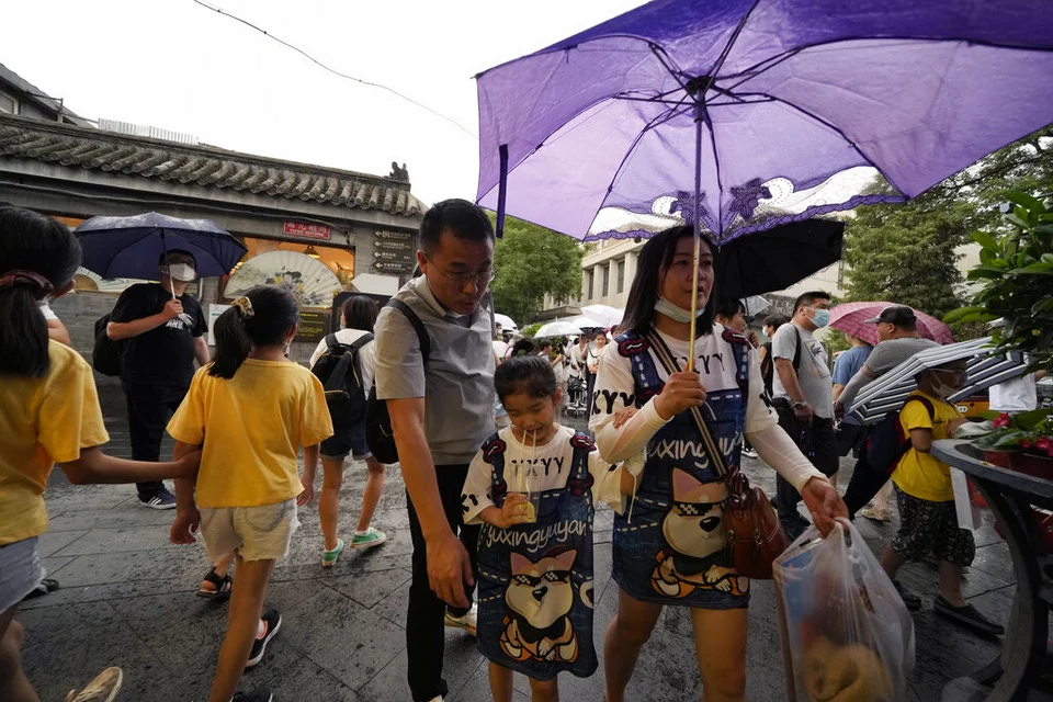 περαστικοί στην Κίνα με μια γυναίκα να κρατά μία μωβ ομπρέλα