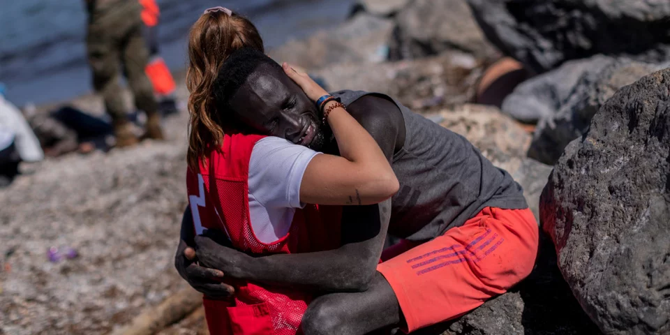 Ένας μετανάστης παρηγορείται από μέλος του ισπανικού Ερυθρού Σταυρού στον ισπανικό θύλακα της Θέουτα, κοντά στα σύνορα του Μαρόκου με την Ισπανία, στις 18 Μαΐου 2021. Φωτογραφία: AP Photo/Bernat Armangue