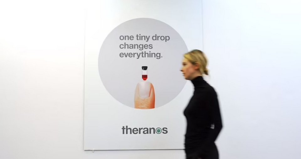  Η Ελίζαμπεθ Χολμς περνά από αφίσα της Theranos