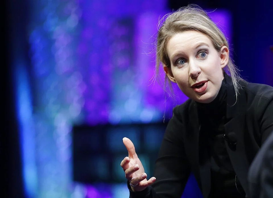 η Ελίζαμπεθ Χολμς με μαύρα ρούχα μιλά σε εκδήλωση