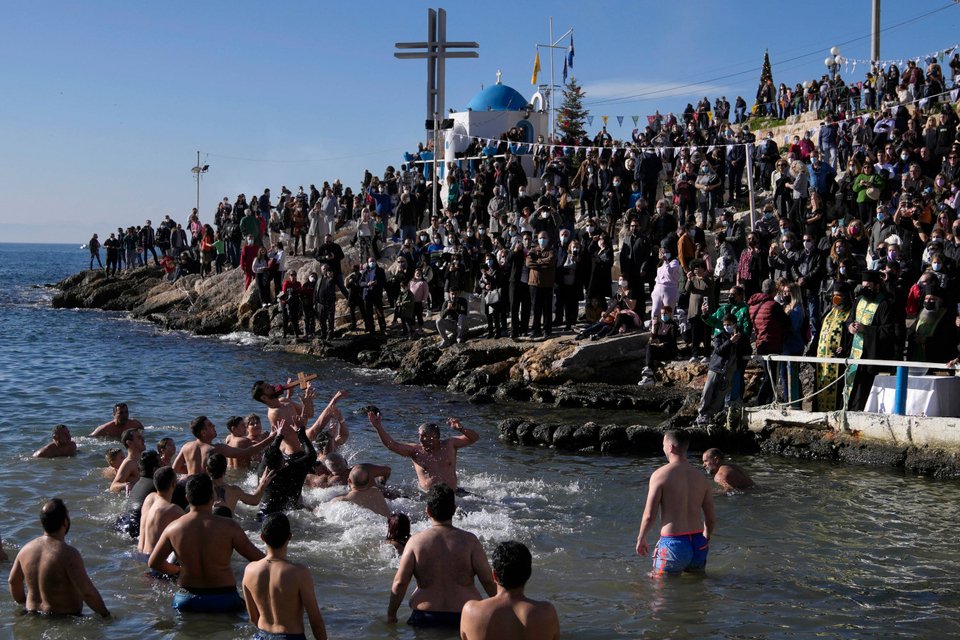 Πηδούν για να πιάσουν τον Σταυρό κατά τη διάρκεια τελετής ευλογίας του νερού για τον εορτασμό των Θεοφανείων στο λιμάνι του Πειραιά/ AP Photo/Thanassis Stavrakis