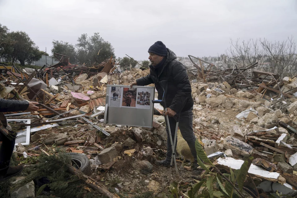 Παλαιστίνιος άνδρας μαζεύει φωτογραφίες από τα ερείπια του σπιτιού / Φωτογραφία: AP Photo/Mahmoud Illean 