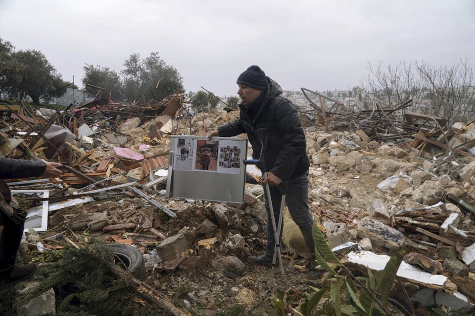 Παλαιστίνιος άνδρας μαζεύει φωτογραφίες από τα ερείπια του σπιτιού / Φωτογραφία: AP Photo/Mahmoud Illean