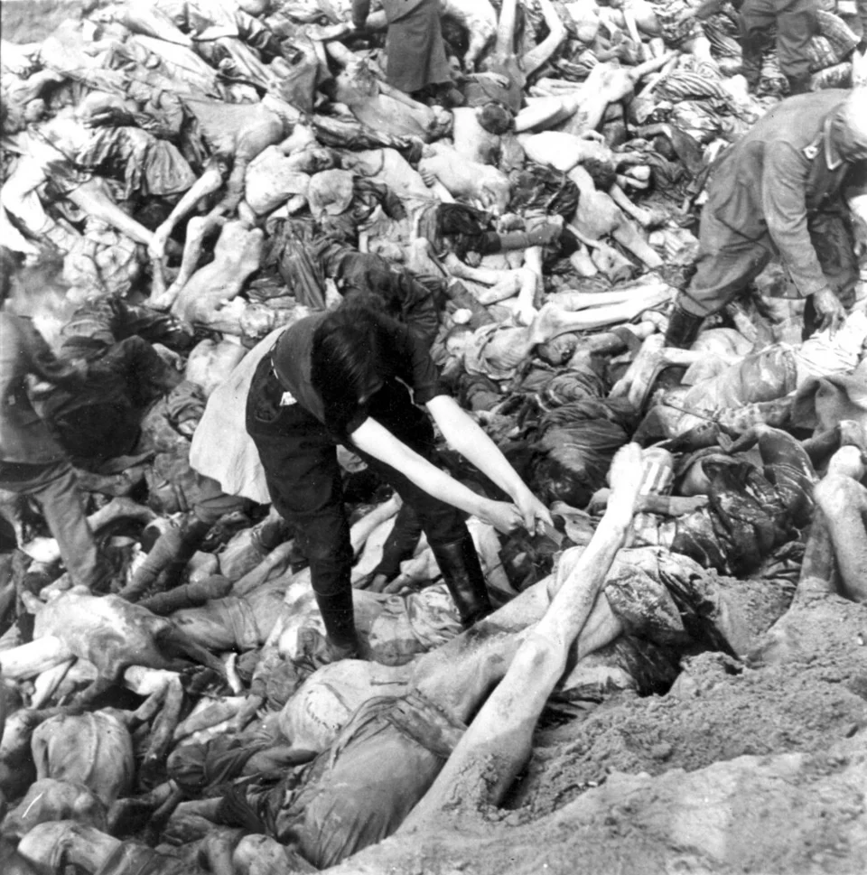 Μια γυναίκα φρουρός των SS μεταφέρει ένα πτώμα σε έναν ομαδικό τάφο για σκοτωμένους κρατούμενους στο ναζιστικό στρατόπεδο συγκέντρωσης στο Μπέργκεν-Μπέλσεν 