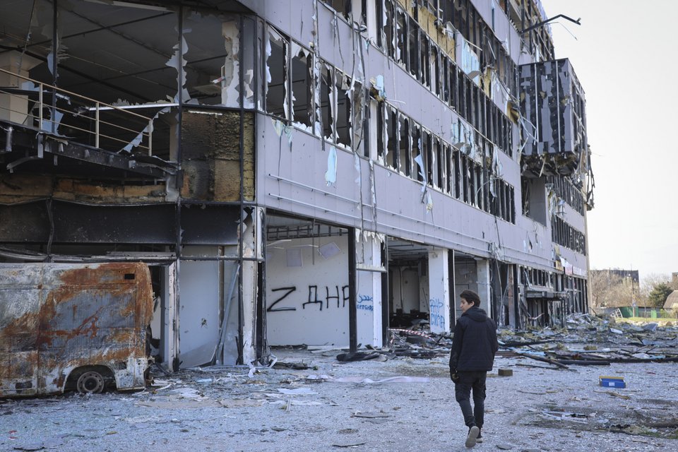 Άνδρας περπατά μπροστά από κατεστραμμένο κτίριο στη Μαριούπολη