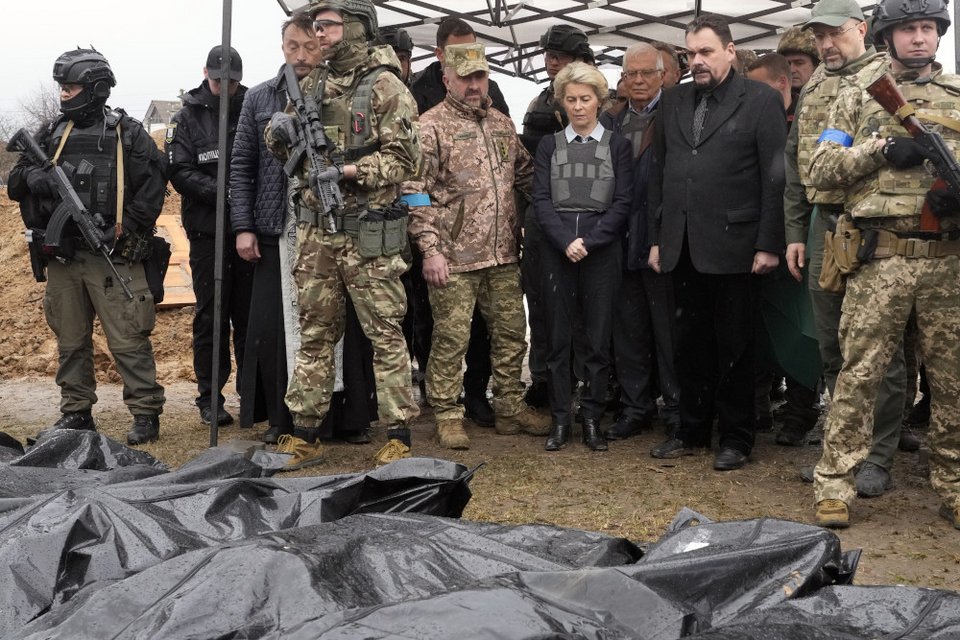 Η Πρόεδρος της Κομισιόν Ούρσουλα Φον ντερ Λάιεν, στο κέντρο, κοιτάζει καλυμμένα πτώματα σκοτωμένων αμάχων στη Μπούτσα, στα περίχωρα του Κιέβου