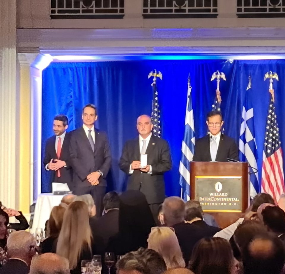 Ο πρωθυπουργός βραβεύει τον father Alex Karloutsos, με το βραβείο να παραλαμβάνει ο γιος του / Φωτογραφία: iefimerida