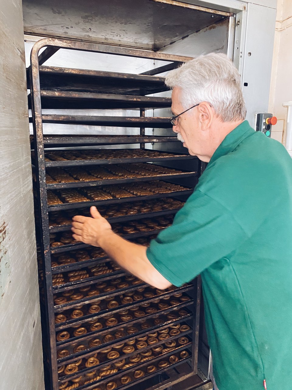 Ο Κώστας Δαρεμάς βάζει τις λαμαρίνες με τα κουλούρια στο φούρνο για ψήσιμο. 