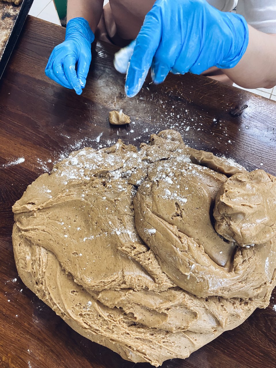 Στη ζύμη ρίχνουν αλεύρι για να πλάσουν τα μουστοκούλουρα. 